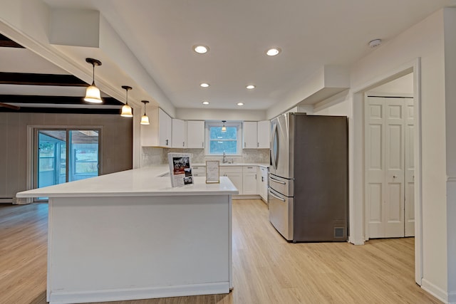 kitchen with kitchen peninsula, white cabinetry, stainless steel refrigerator, and a healthy amount of sunlight