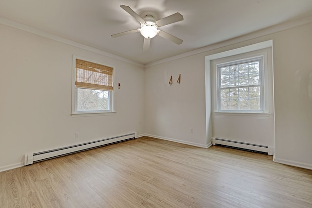 empty room featuring a wealth of natural light, light wood-type flooring, and a baseboard heating unit