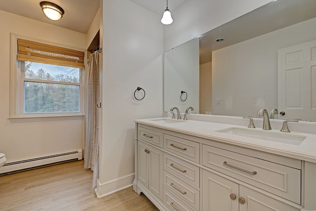 bathroom with hardwood / wood-style floors, vanity, and a baseboard radiator