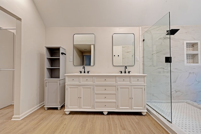 bathroom featuring hardwood / wood-style floors, vanity, and a tile shower