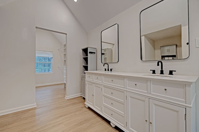 bathroom with hardwood / wood-style floors, vanity, and vaulted ceiling