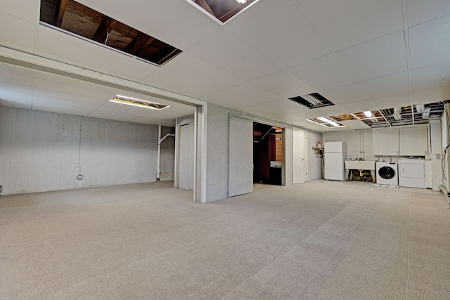 basement featuring light carpet, white refrigerator, washing machine and dryer, and sink