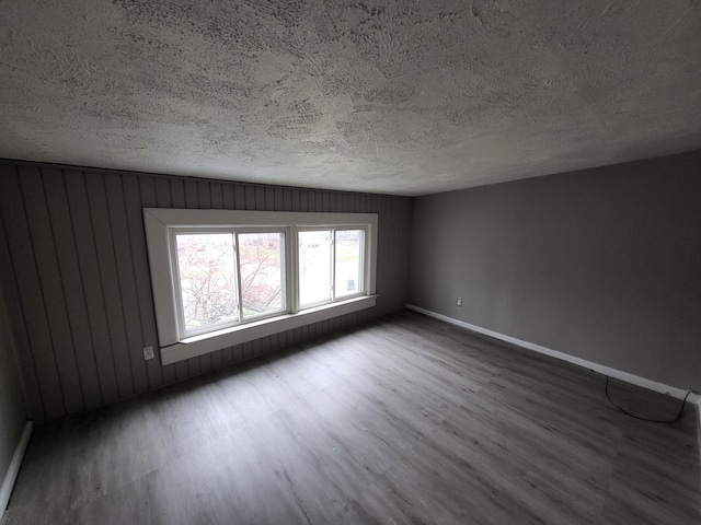 empty room with wooden walls, hardwood / wood-style floors, and a textured ceiling