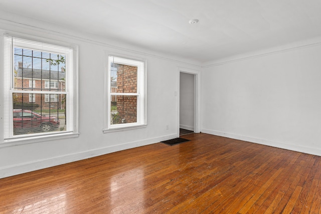 spare room featuring wood-type flooring and crown molding