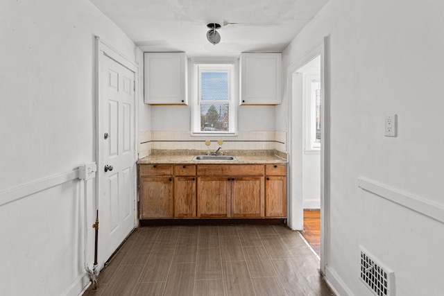 kitchen with white cabinets, light hardwood / wood-style floors, and sink