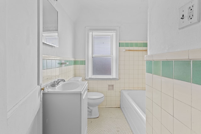 bathroom with vanity, a bath, tile patterned floors, toilet, and tile walls