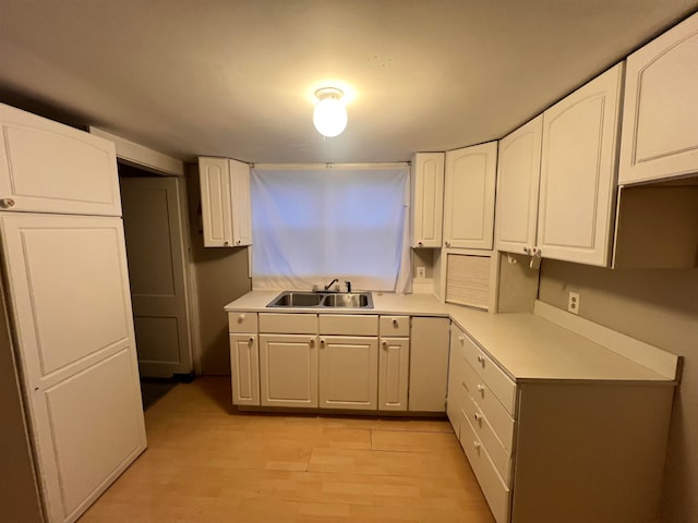 kitchen featuring white cabinets, light hardwood / wood-style flooring, and sink