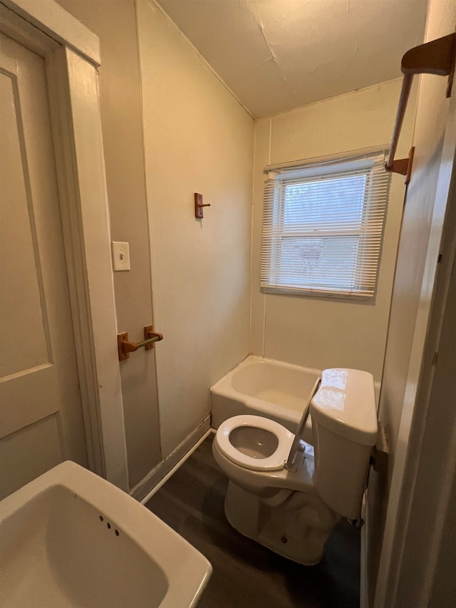 bathroom featuring a tub to relax in, sink, hardwood / wood-style floors, and toilet