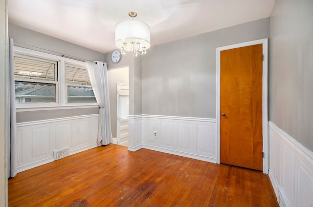 spare room with an inviting chandelier and dark wood-type flooring