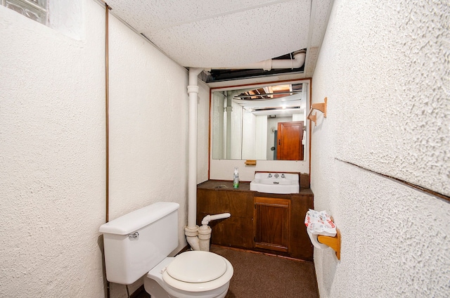 bathroom featuring toilet, vanity, a paneled ceiling, and a textured wall