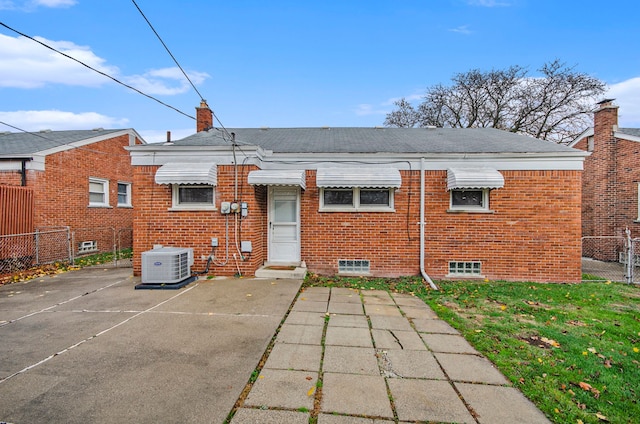 rear view of house with central air condition unit, fence, and brick siding