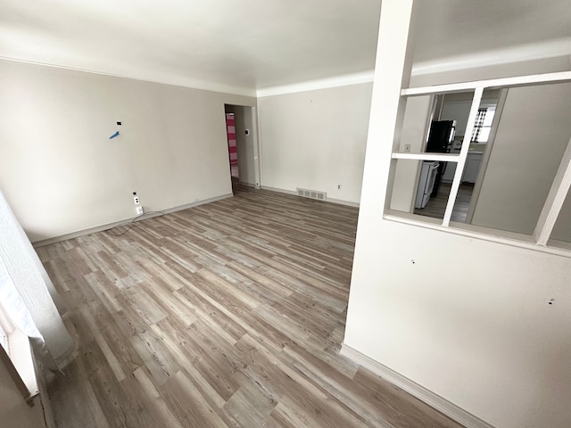 unfurnished living room featuring wood finished floors, visible vents, and baseboards