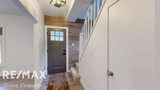 foyer entrance with wood-type flooring and wooden walls