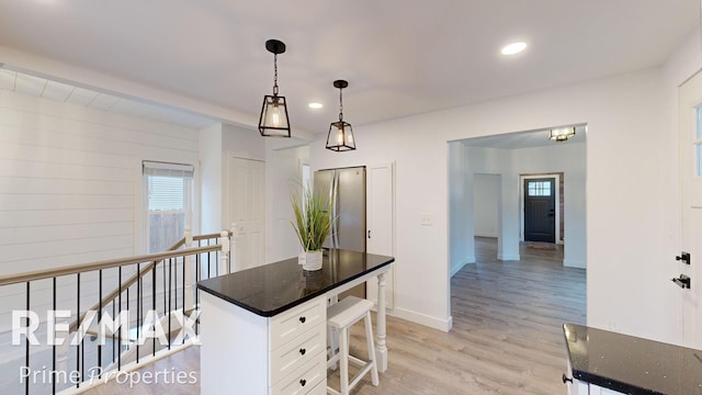 kitchen with a kitchen island, light hardwood / wood-style flooring, white cabinetry, and a healthy amount of sunlight