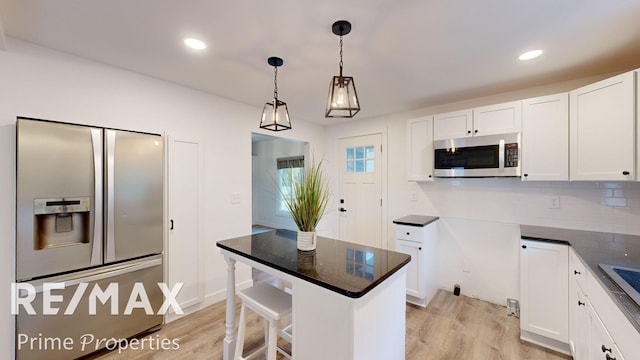 kitchen with white cabinets, pendant lighting, stainless steel appliances, and light hardwood / wood-style floors