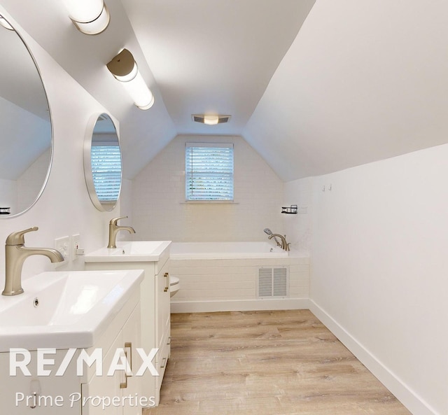 bathroom featuring a relaxing tiled tub, wood-type flooring, lofted ceiling, and toilet