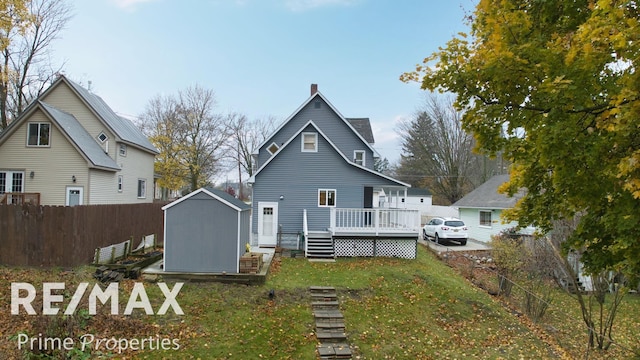 back of property featuring a lawn, a wooden deck, and a shed