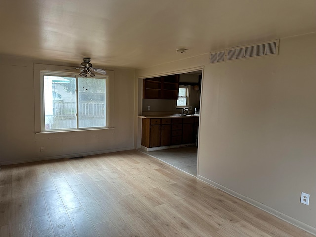 unfurnished living room with ceiling fan, light wood-type flooring, and sink