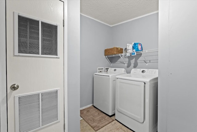 washroom featuring washing machine and dryer, crown molding, and a textured ceiling