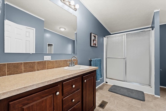 bathroom featuring a textured ceiling, vanity, an enclosed shower, and lofted ceiling