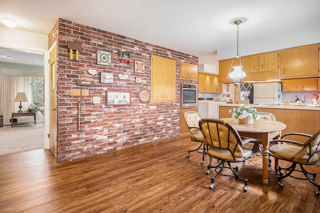 dining space featuring washer / clothes dryer, wood-type flooring, and brick wall