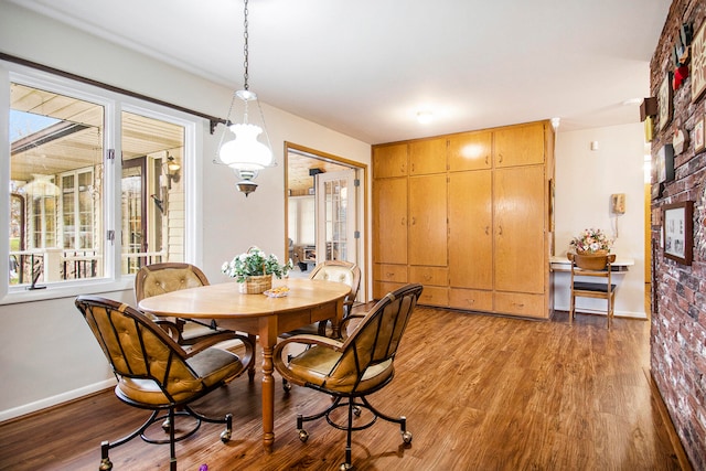 dining space featuring hardwood / wood-style floors and brick wall