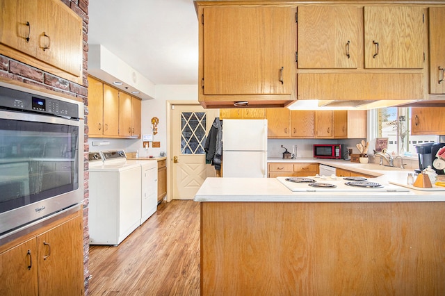 kitchen with kitchen peninsula, white appliances, sink, independent washer and dryer, and light hardwood / wood-style floors