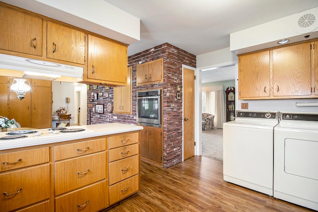 kitchen featuring separate washer and dryer, dark hardwood / wood-style flooring, oven, and brick wall