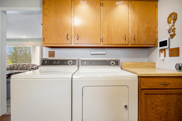 washroom with washer and dryer and cabinets