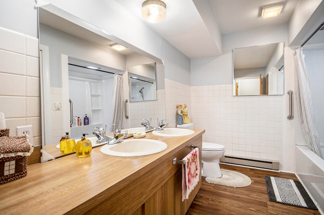 full bathroom featuring vanity, hardwood / wood-style flooring, toilet, baseboard heating, and tile walls