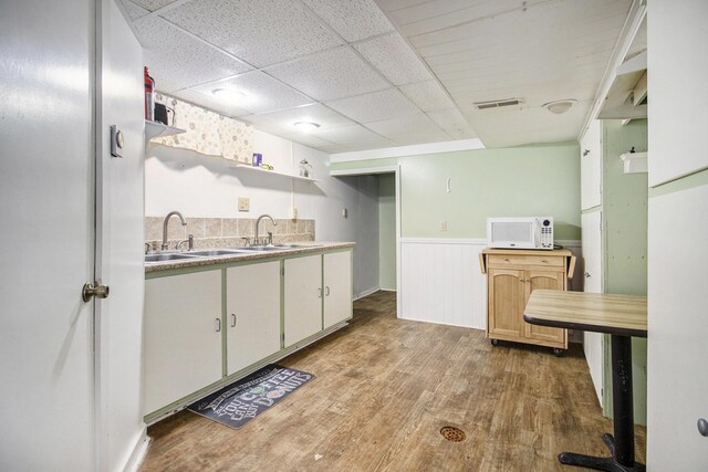 7349 E Main St, Eau Claire, MI 49111 - kitchen featuring open shelves, white microwave, a sink, a wainscoted wall, and light wood-style floors