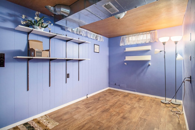 basement with wood walls and hardwood / wood-style flooring