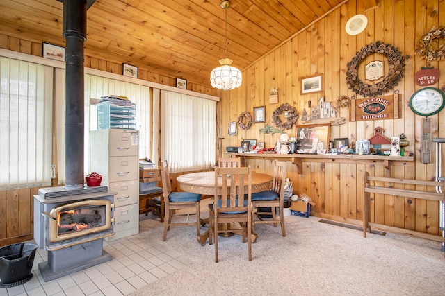 dining room with wood walls, a wood stove, and light carpet