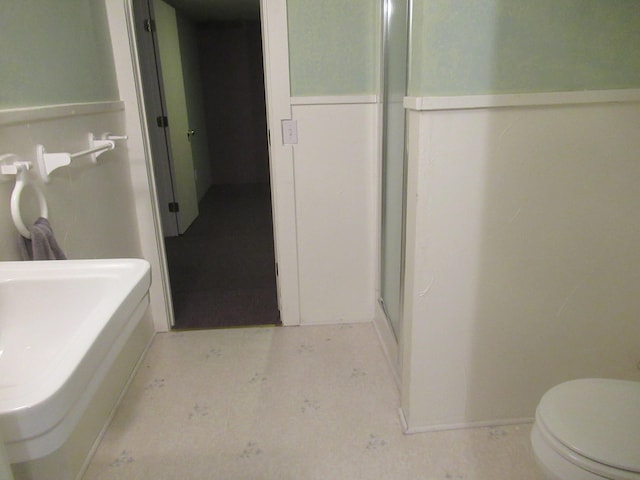 bathroom featuring a shower with shower door and toilet