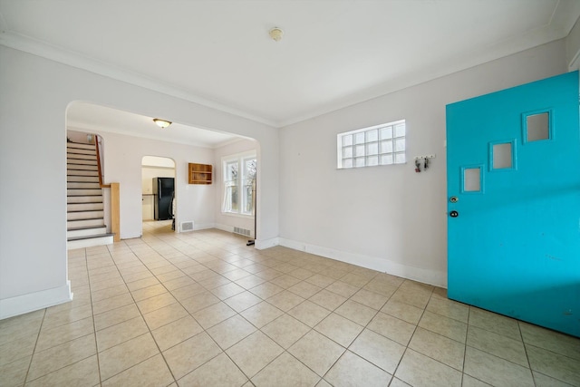 foyer entrance with light tile patterned floors and crown molding