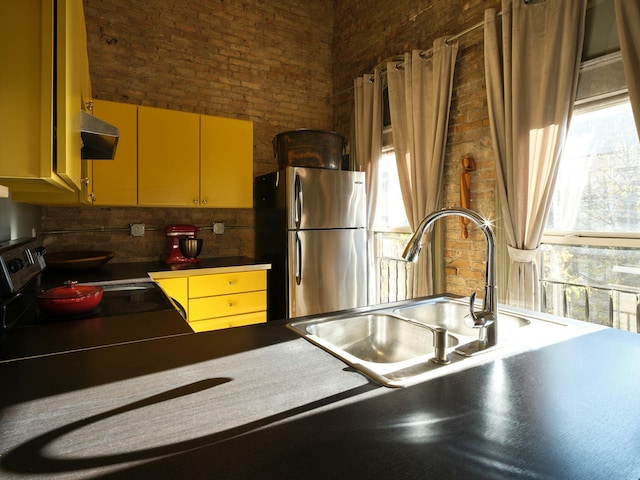 kitchen featuring brick wall and stainless steel refrigerator