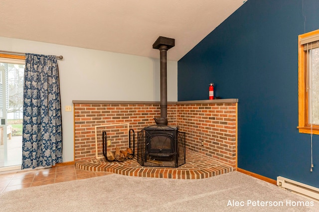 unfurnished living room featuring baseboard heating, a wood stove, tile patterned floors, and lofted ceiling