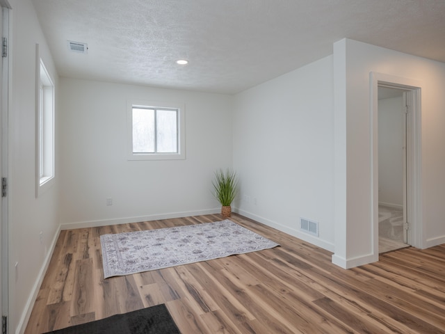 spare room featuring a textured ceiling and hardwood / wood-style floors