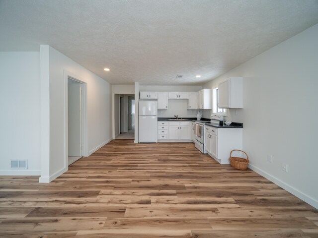 kitchen featuring light hardwood / wood-style floors, white appliances, a textured ceiling, white cabinets, and sink