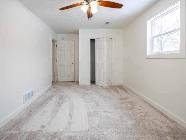 unfurnished bedroom with ceiling fan and light colored carpet