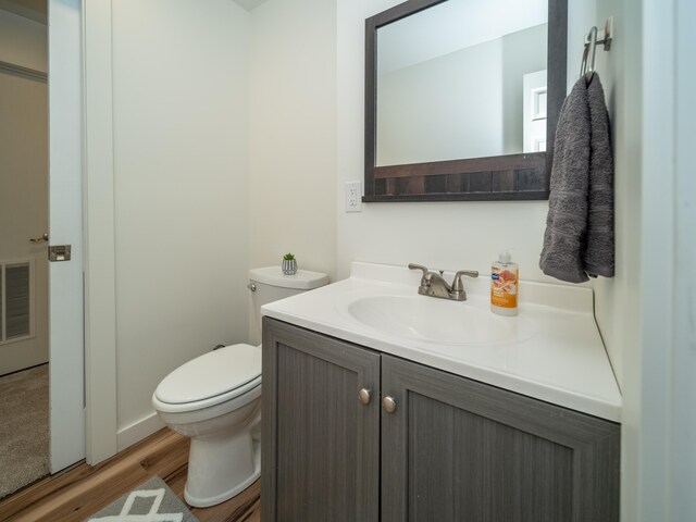 bathroom with toilet, wood-type flooring, and vanity