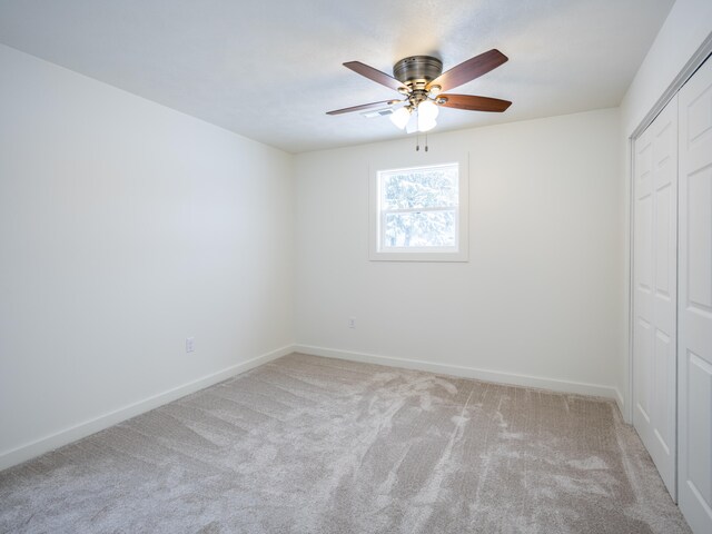 unfurnished bedroom with ceiling fan, light colored carpet, and a closet