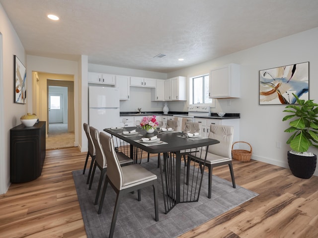 dining space featuring sink, a textured ceiling, and light wood-type flooring