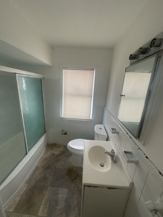 full bathroom with vanity, enclosed tub / shower combo, tile walls, and toilet