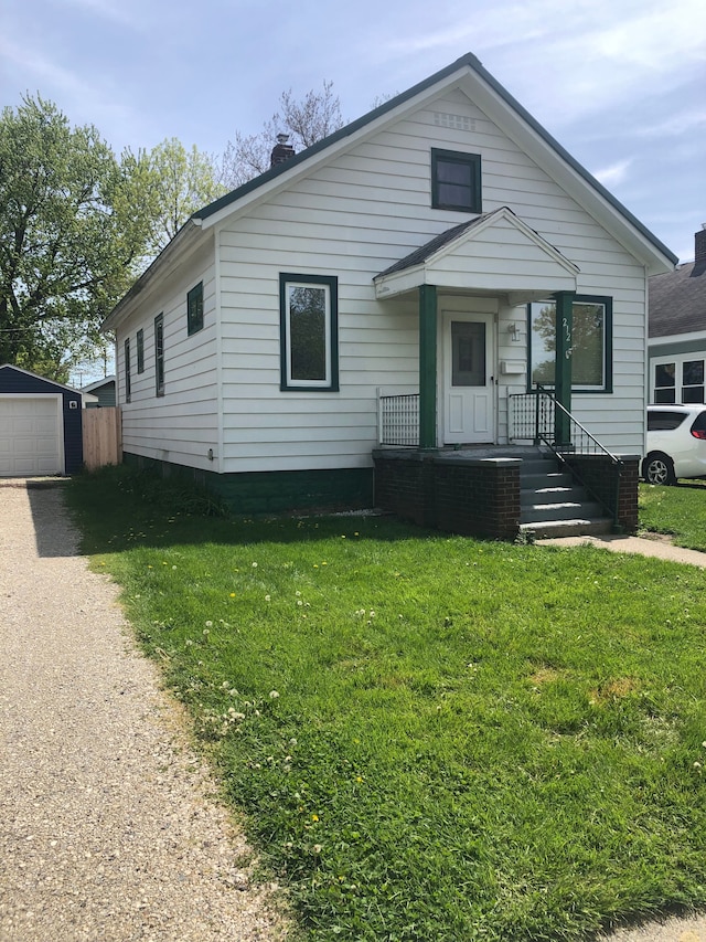 view of front of house featuring a garage, an outbuilding, and a front yard