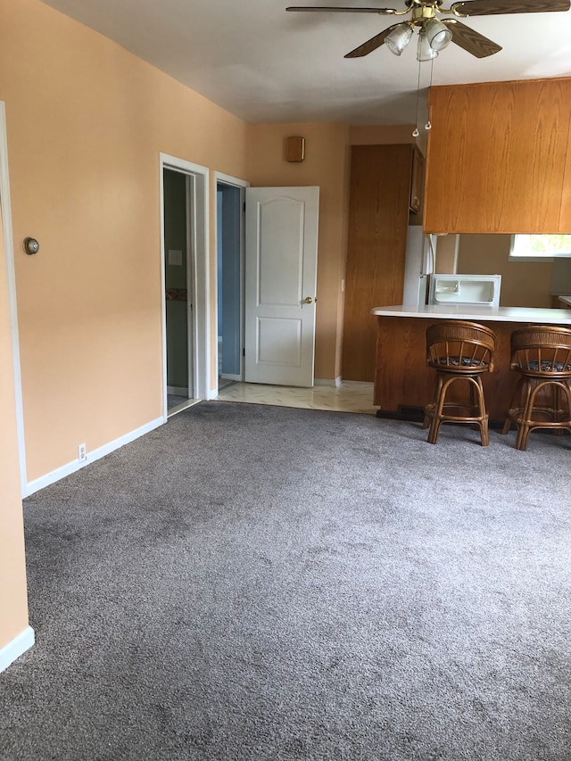 kitchen with kitchen peninsula, ceiling fan, and carpet floors