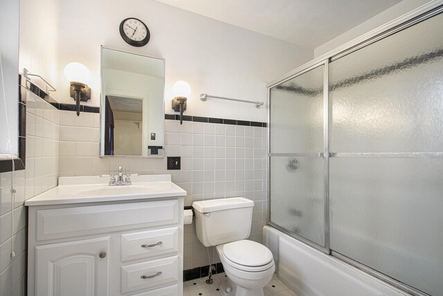 1806 Bond St, Niles, MI 49120 - full bath with tile walls, vanity, toilet, combined bath / shower with glass door, and tile patterned flooring