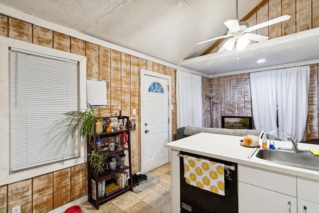 kitchen with dishwasher, white cabinets, sink, vaulted ceiling, and ceiling fan