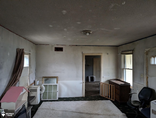 bedroom with multiple windows, dark carpet, and a textured ceiling