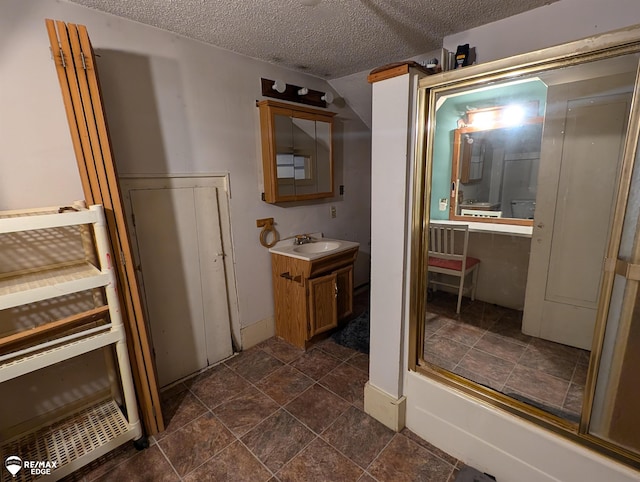 bathroom featuring vanity, a textured ceiling, and enclosed tub / shower combo